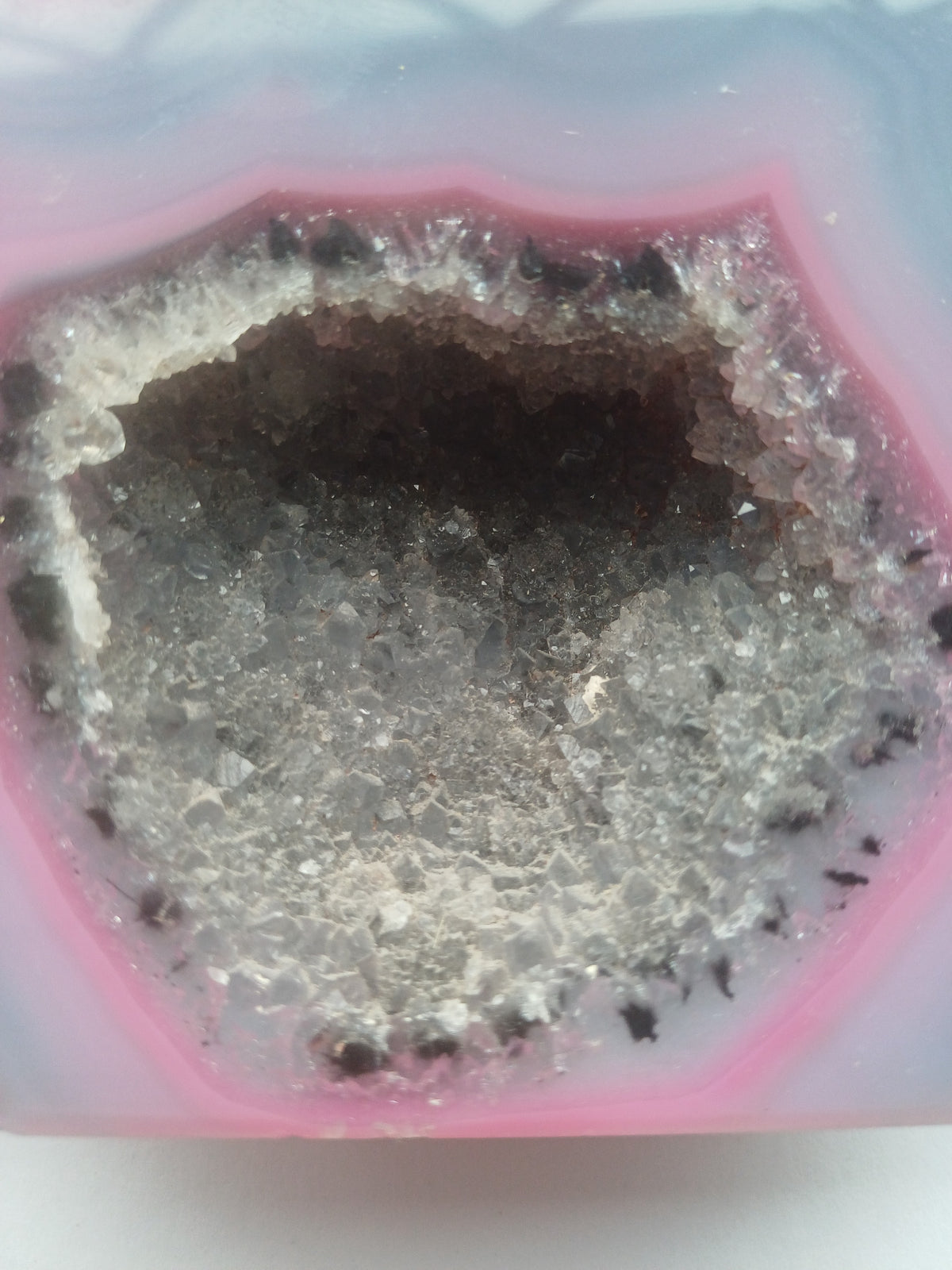 Close-up of sparkling druzy quartz crystal cavity in colour-enhanced pink and blue agate