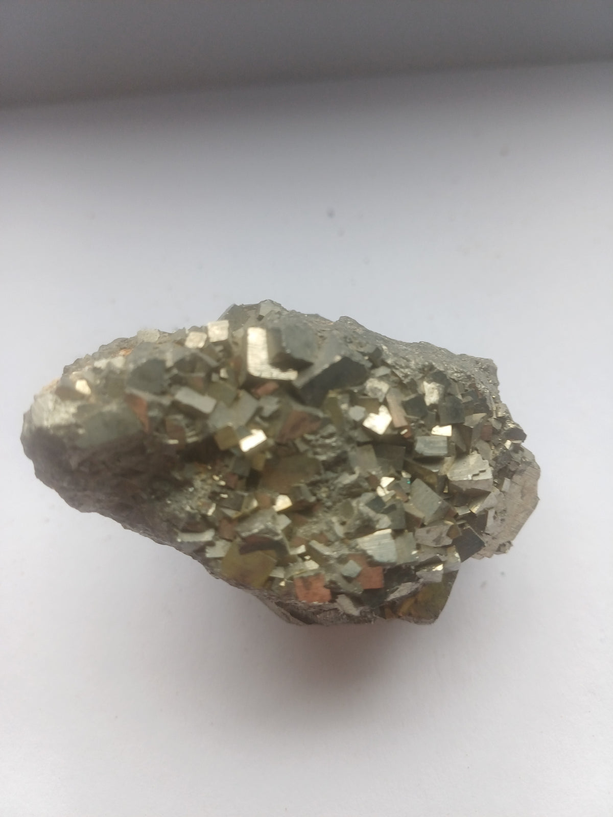 Natural pyrite cluster shown beside a UK one pound coin for scale