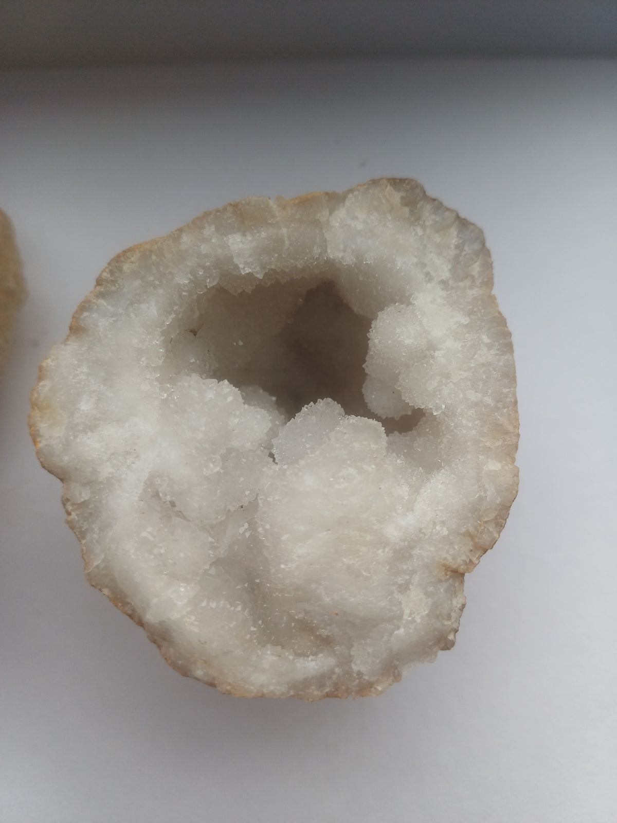 Close-up of white druzy quartz crystals inside the smaller geode half