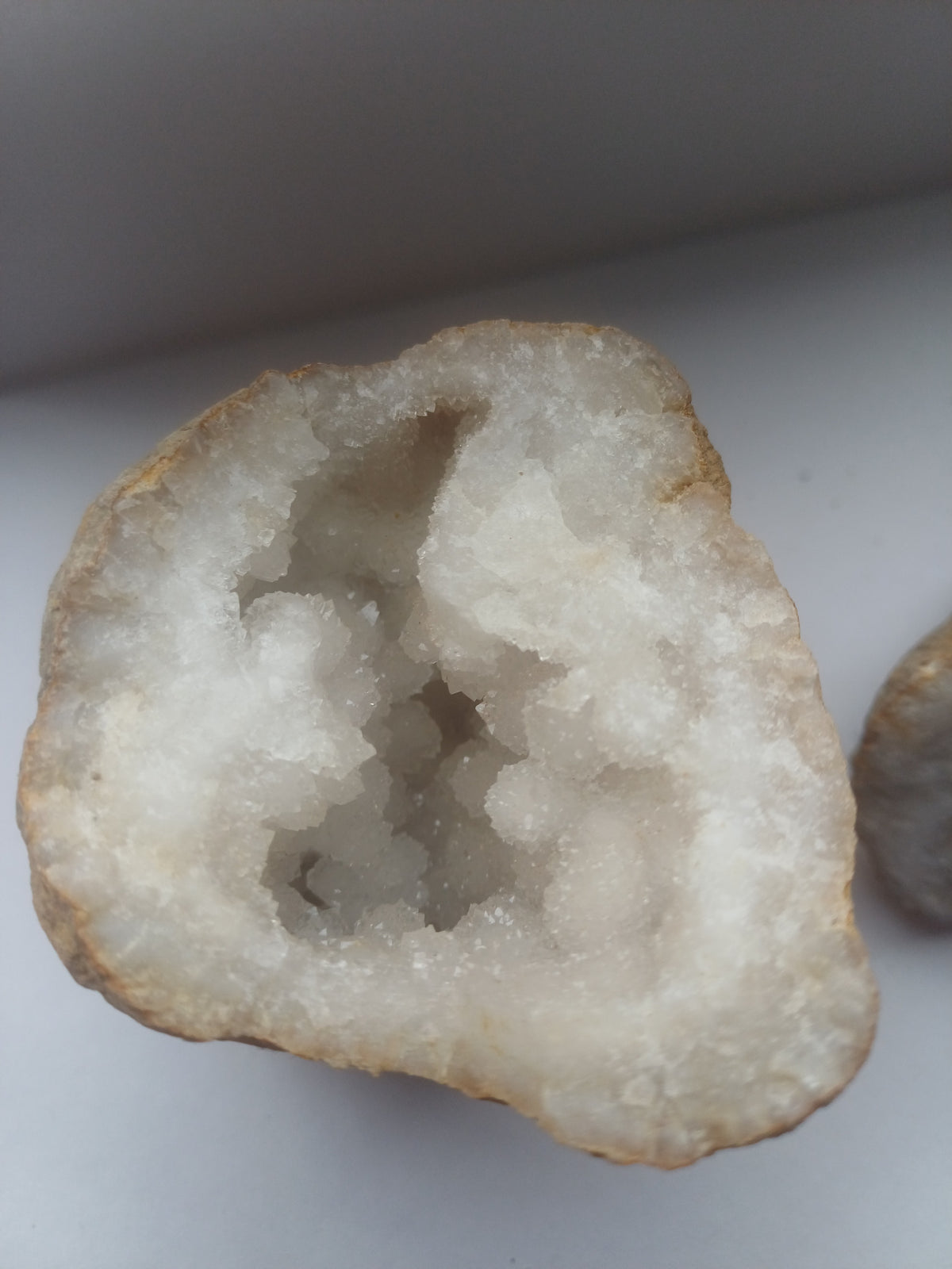 Larger half of natural split quartz geode showing deep sparkling white crystal cavity