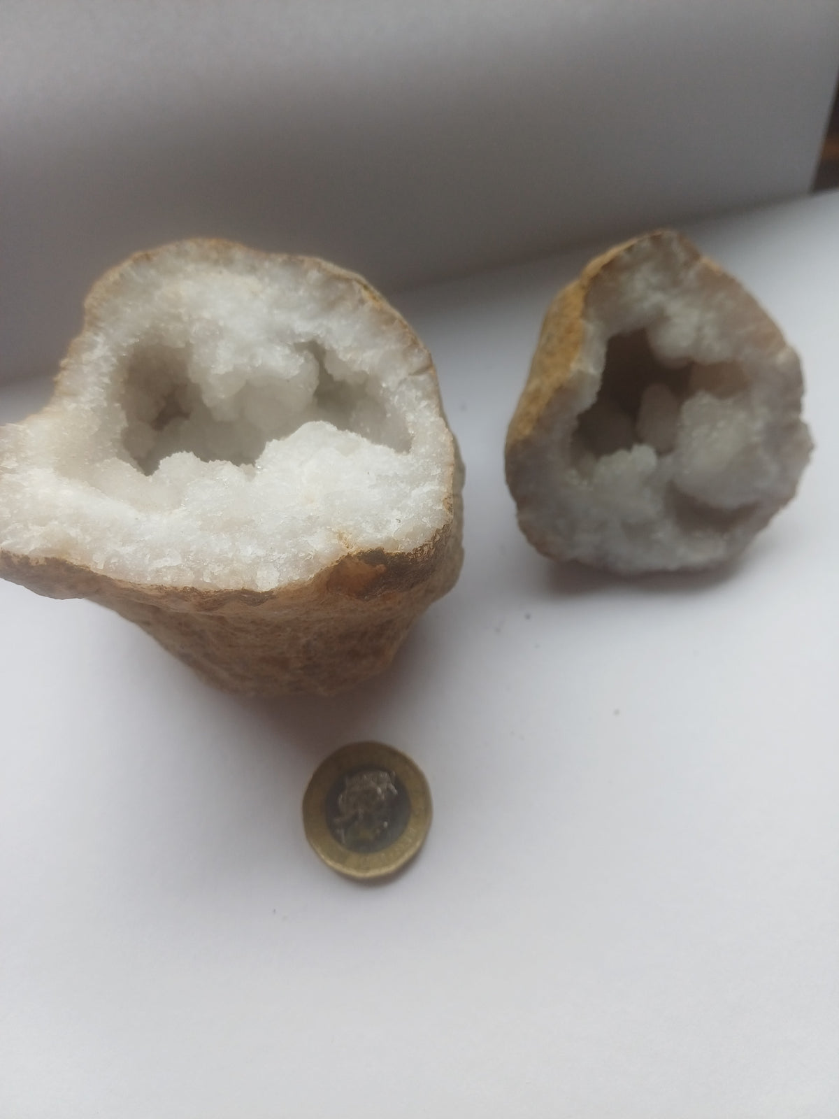 Matched quartz geode halves together with a UK one pound coin for scale