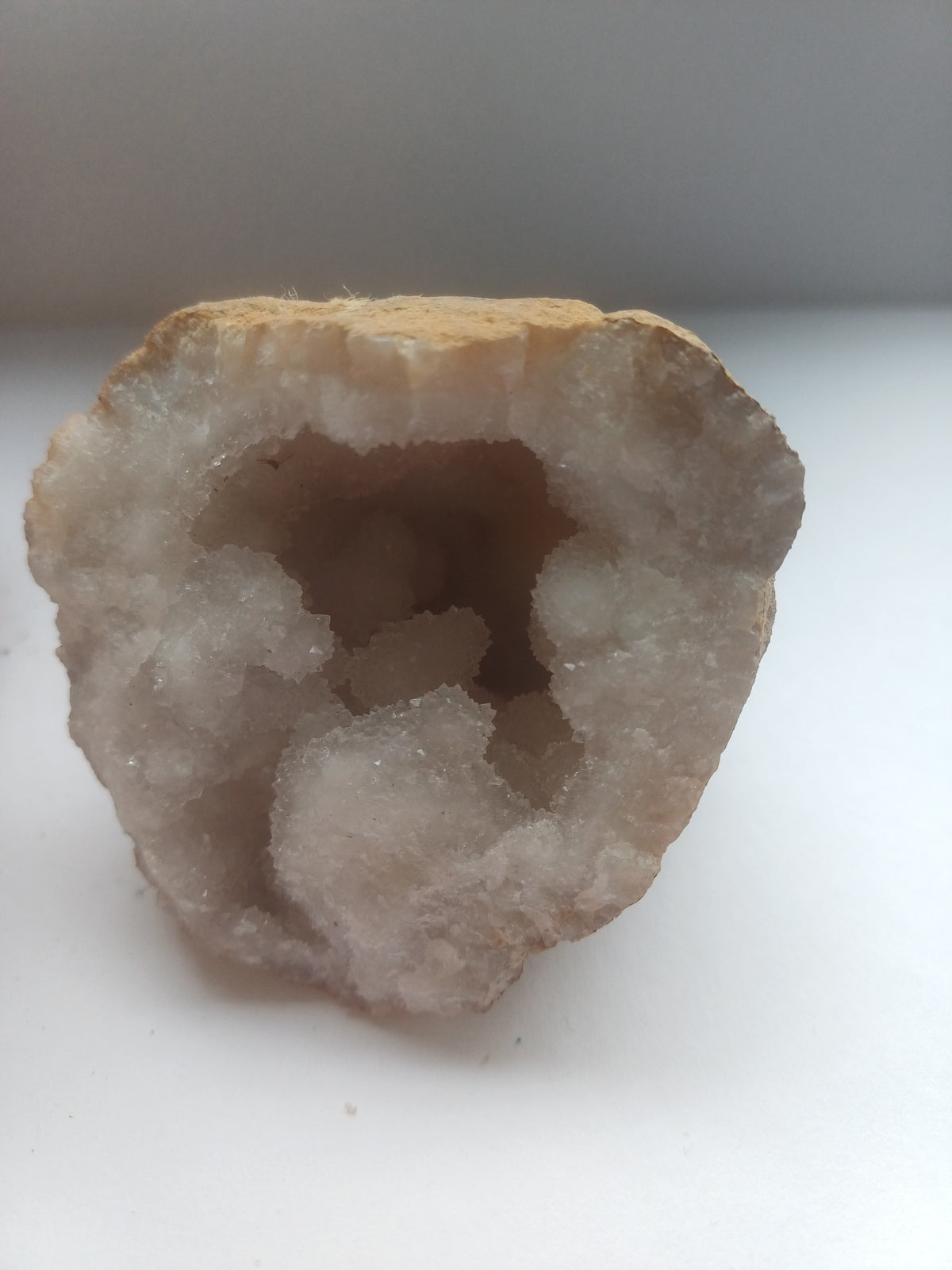Smaller half of matched split quartz geode with white sparkling crystal interior