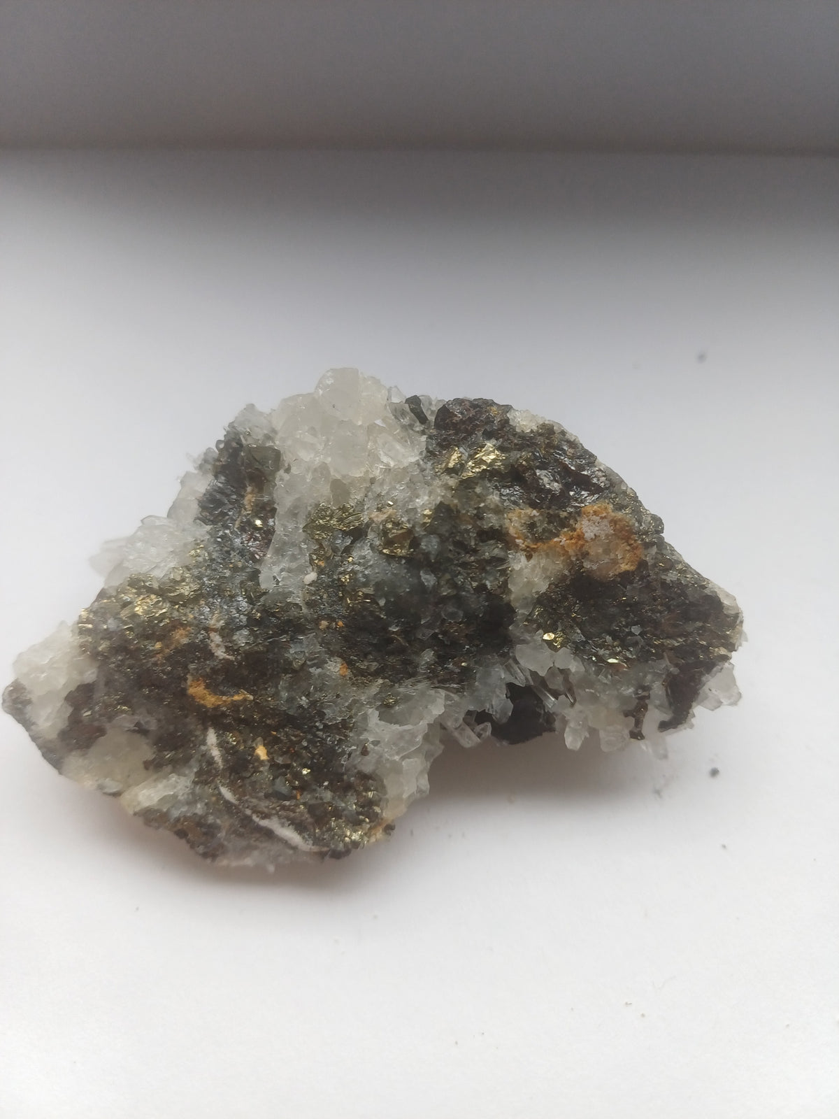 Quartz crystal mineral specimen with metallic brassy and dark sulphide mineral areas, side view