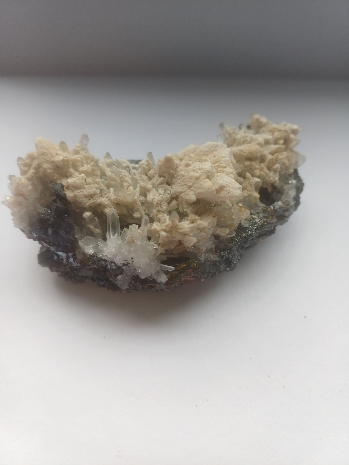 Mixed mineral specimen detail showing cream crystal matrix over dark crystals with clear quartz points