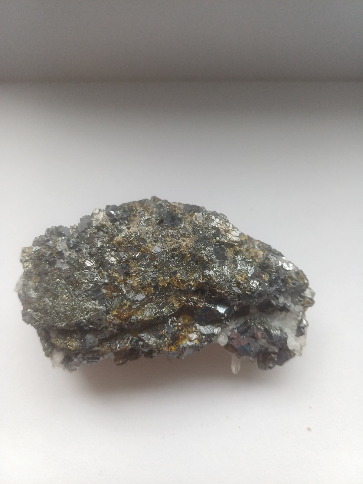 Mixed mineral specimen reverse view showing dense dark metallic crystal growth